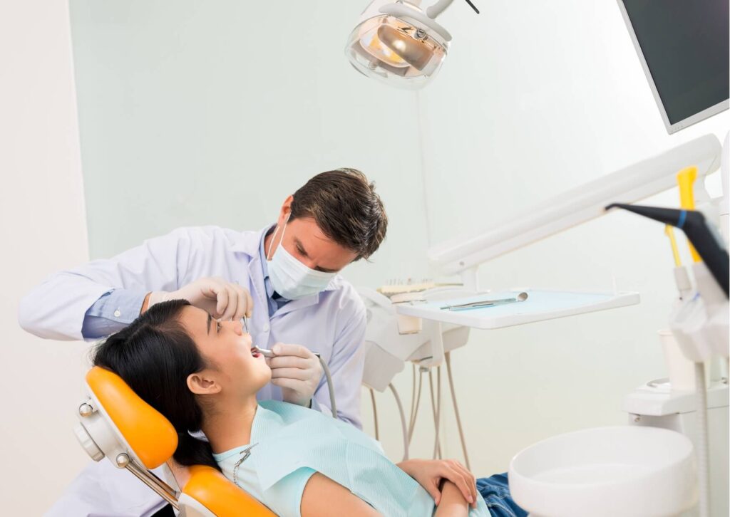 Dentist examining a patient's teeth during a consultation to determine whether a dental crown or veneers are the best treatment option.